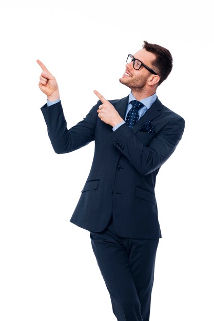 Sonriente joven empresario apuntando al espacio de la copia