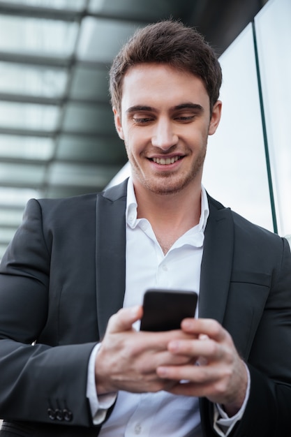 Sonriente joven empresario caminando cerca del centro de negocios charlando