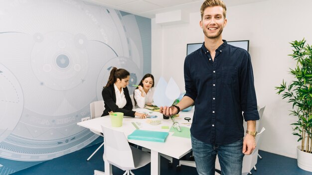 Sonriente joven empresario con icono de gota de agua de pie en la oficina