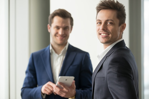 Sonriente joven empresario mirando a cámara, desarrollar aplicación