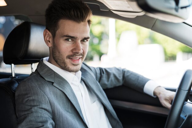 Sonriente joven empresario viaja en coche