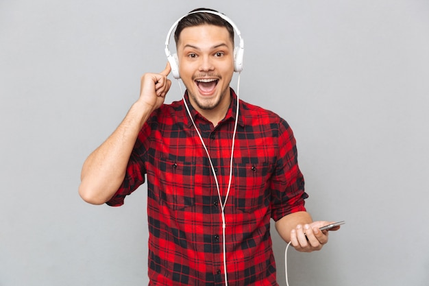 Sonriente joven escuchando música con auriculares.