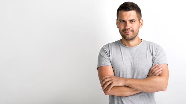 Sonriente joven guapo con el brazo cruzado sobre fondo blanco