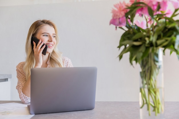 Foto gratuita sonriente joven hablando por teléfono móvil