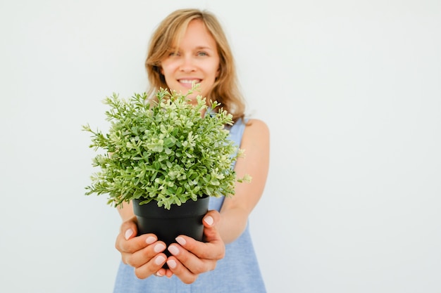 Foto gratuita sonriente joven hermosa mujer dar planta potted