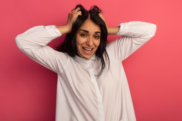 Sonriente joven hermosa mujer vestida con camiseta blanca agarró el pelo