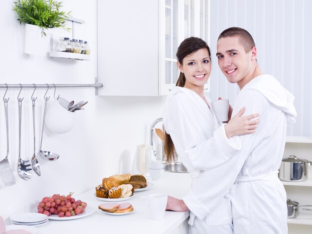 Sonriente joven hermosa pareja abrazándose en la cocina