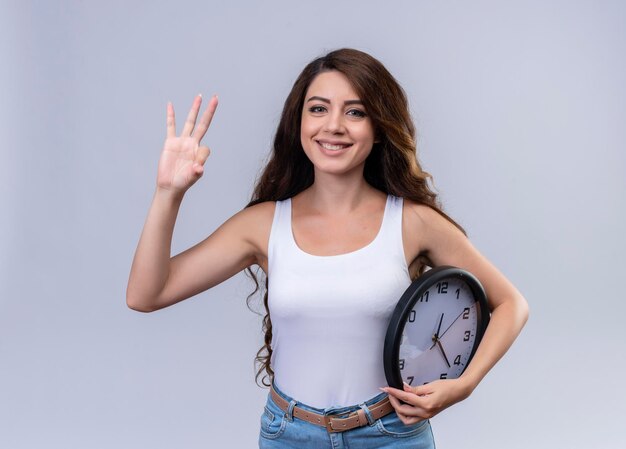 Sonriente joven hermosa sosteniendo el reloj y mostrando tres