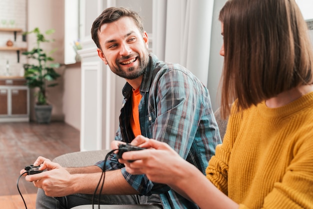 Foto gratuita sonriente joven jugando el videojuego con su esposa