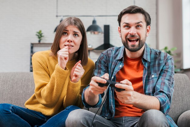 Sonriente joven jugando el videojuego con su esposa
