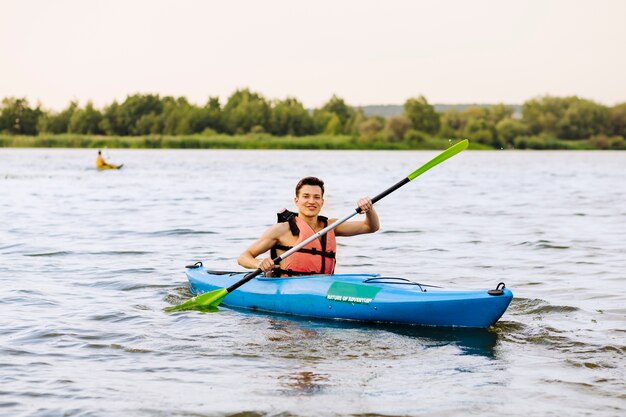 Sonriente joven kayak en el lago