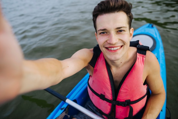 Sonriente joven kayakista tomando selfie