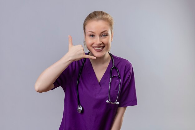 Sonriente joven médico vistiendo un estetoscopio y bata médica púrpura