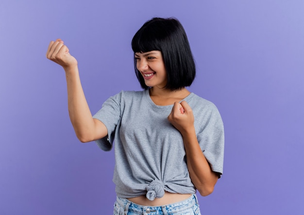 Foto gratuita sonriente joven morena caucásica mantiene los puños mirando al lado