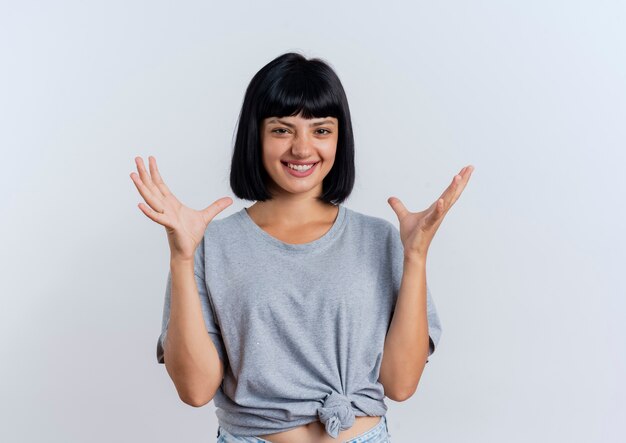 Sonriente joven morena mujer caucásica se encuentra con las manos levantadas