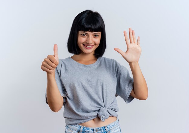 Sonriente joven morena mujer caucásica gestos seis con los dedos