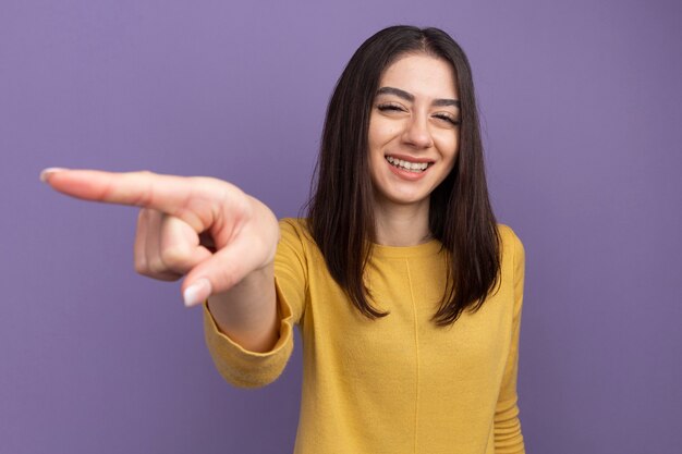 Sonriente joven mujer bastante caucásica apuntando al lado