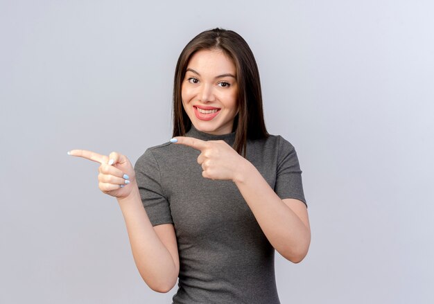 Sonriente joven mujer bonita apuntando al lado aislado sobre fondo blanco con espacio de copia