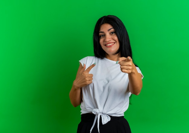 Sonriente joven mujer caucásica apunta a la cámara con las dos manos