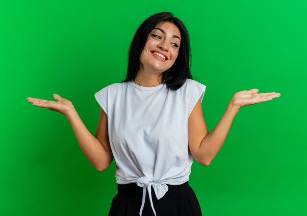 Sonriente joven mujer caucásica mantiene las manos abiertas mirando al lado