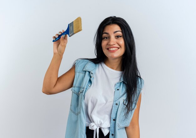 Sonriente joven mujer caucásica sostiene pincel