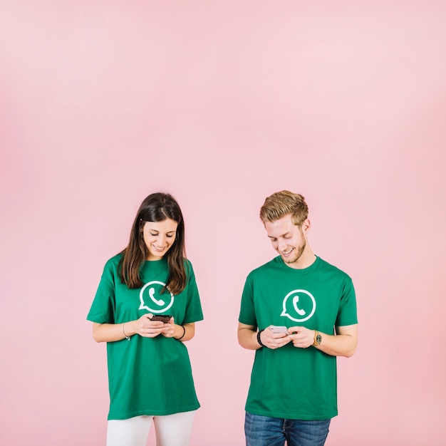 Sonriente joven y mujer mirando celular