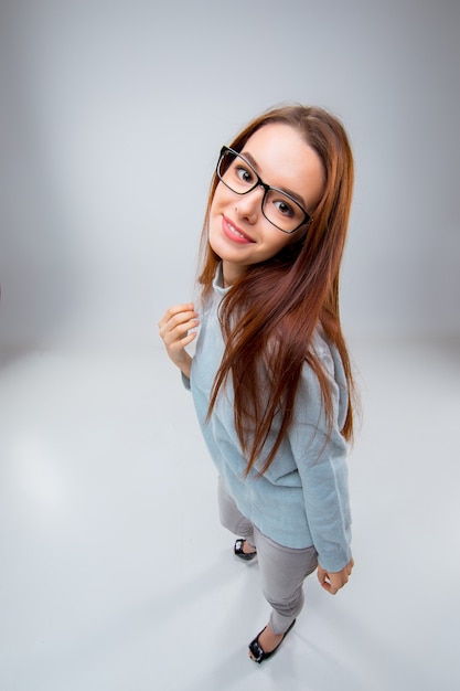 Foto gratuita la sonriente joven mujer de negocios en pared gris