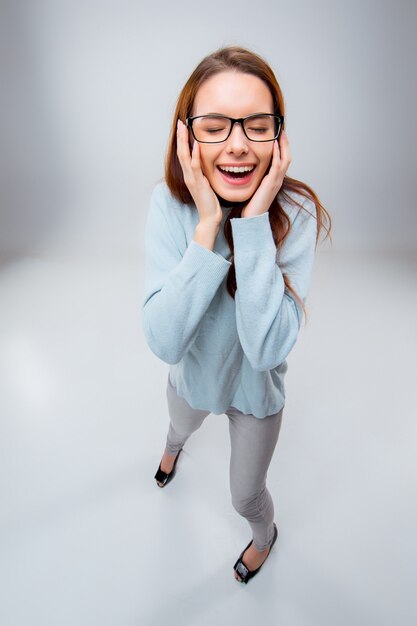 Sonriente a joven mujer de negocios en vasos sobre un fondo gris. Vista superior