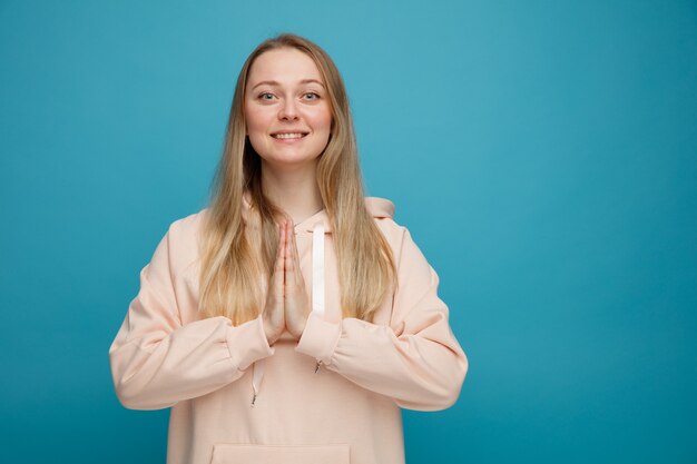 Sonriente joven mujer rubia haciendo gesto de namaste