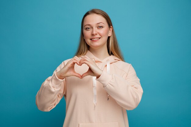 Sonriente joven mujer rubia haciendo signo de amor