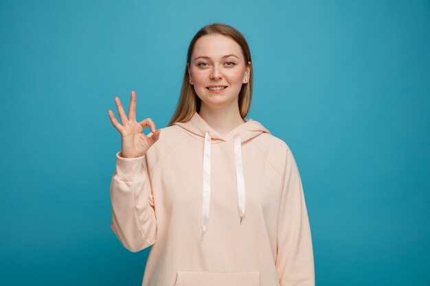 Sonriente joven mujer rubia haciendo el signo de ok