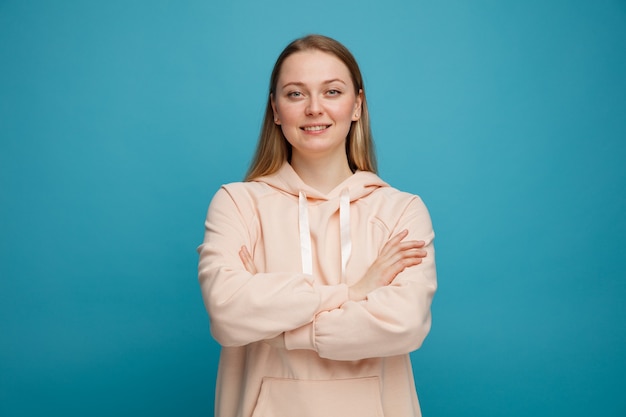 Sonriente joven mujer rubia de pie con postura cerrada