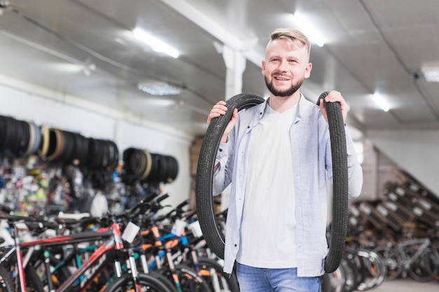 Sonriente joven con neumáticos de bicicleta en la tienda