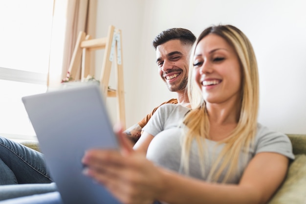 Sonriente joven pareja mirando tableta digital