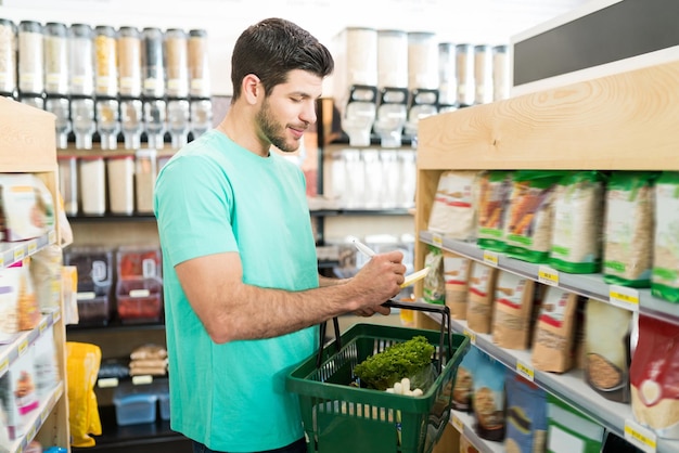 Sonriente joven revisando la lista de compras en el supermercado