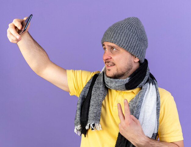 Sonriente joven rubio eslavo enfermo vistiendo gorro de invierno