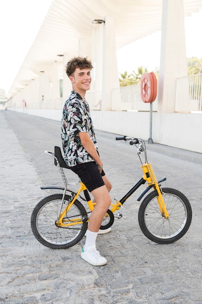 Foto gratuita sonriente joven sentado en bicicleta