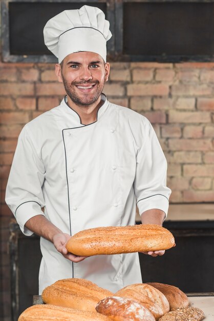 Sonriente joven sosteniendo una barra de pan