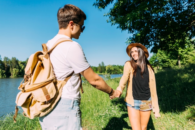 Sonriente joven sosteniendo la mano de novio en el parque