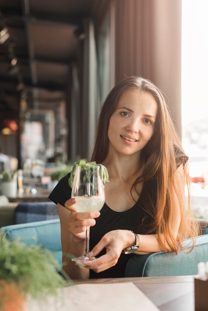 Sonriente joven sosteniendo un vaso de bebida en el restaurante