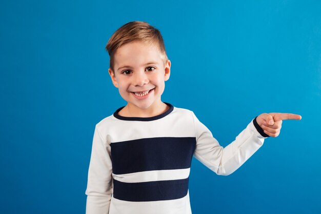 Sonriente joven en suéter apuntando lejos