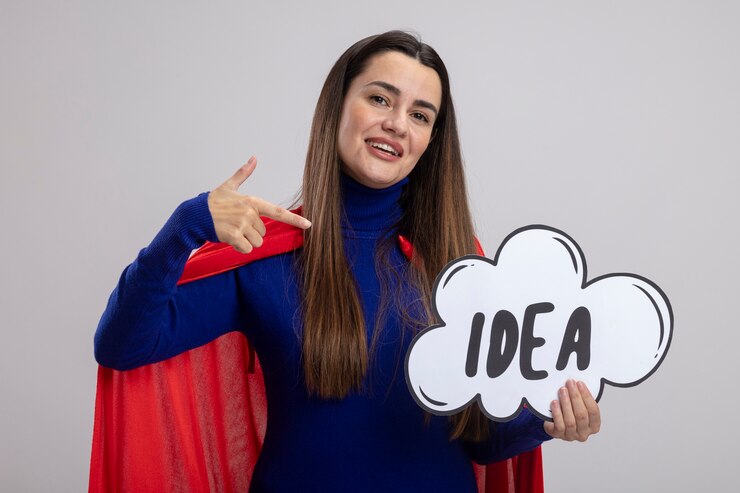 Foto gratuito sonriente joven superhéroe sosteniendo y apunta a la burbuja de la idea aislada sobre fondo blanco.