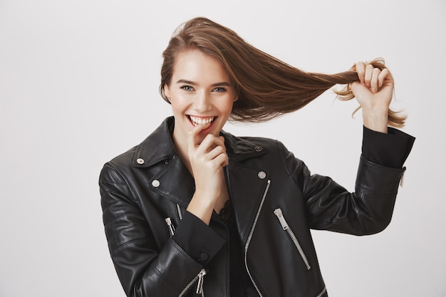 Sonriente joven tirar del cabello, concepto de productos para el cuidado del cabello