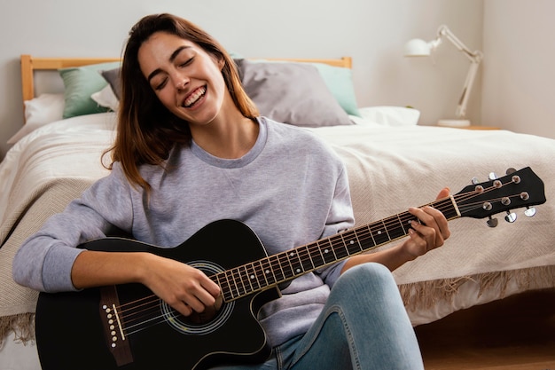 Sonriente joven tocando la guitarra en casa