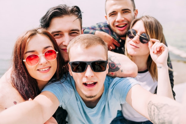 Sonriente joven tomando selfie con amigos