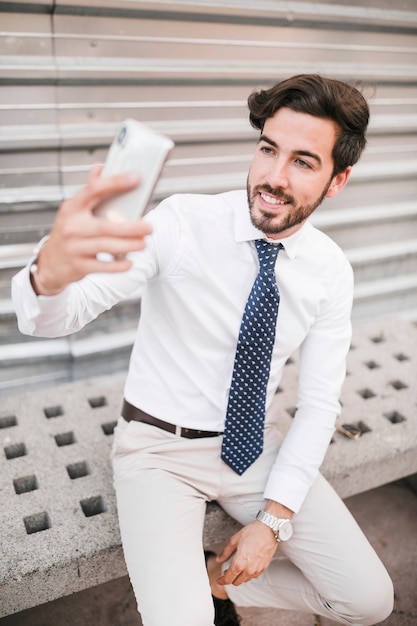 Sonriente joven tomando selfie con teléfono móvil