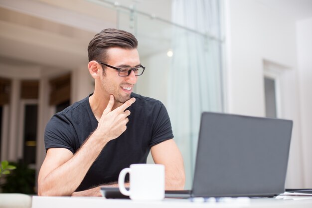 Sonriente joven trabajando en la computadora portátil en casa