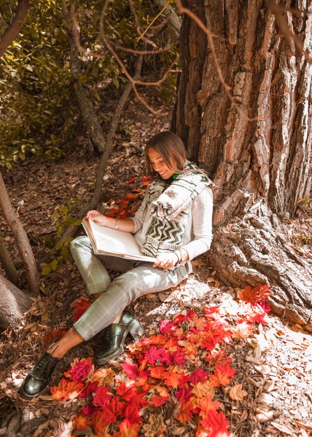 Sonriente lectura femenina en el bosque de otoño