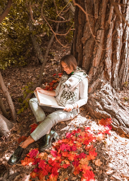 Sonriente lectura femenina en el bosque de otoño