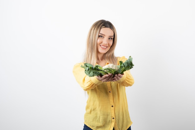 Foto gratuita sonriente modelo de mujer bonita de pie y sosteniendo coliflor.